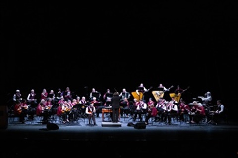 View of full Balalaika Orchestra on a stage with black background