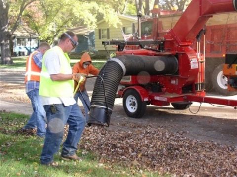 Men collection leaves on truck with hose