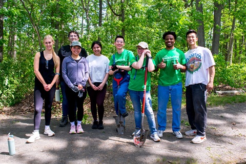 A group of volunteers poses on a forested trail.