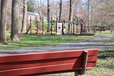 Red bench in front of children's playground at Cardinal Park